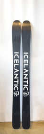 Two black Icelantic Demo - 23/24 Riveter 104 skis stand upright against a white background, featuring the bold white ICELANTIC brand name on each ski and the Icelantic logo near the base. Designed as all-mountain women's demo skis, they combine style and versatility for skiers seeking adventure.