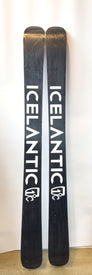 A pair of black Icelantic Demo - 23/24 Nomad 115 skis, handmade in Colorado, stand upright against a white background, displaying the white Icelantic logo and text on the base of each big mountain freeride ski.