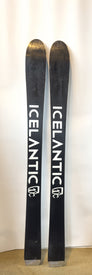 Two black Icelantic Demo - 23/24 Shaman 2.0 99 skis stand upright against a white background. Each ski prominently displays the ICELANTIC brand name and logo in large white lettering from top to bottom. These demo skis are ideal for anyone eager to experience cutting-edge design and performance.