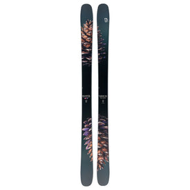 A pair of Icelantic Skis Torrent 102, black with intricate pine cone graphics in brown and purple hues, stand vertically side by side on a white background.
