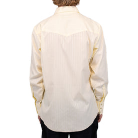A person shown from the back against a plain white background is wearing the Wrangler Agave Pearl Snap Shirt by Icelantic Skis, a light yellow long-sleeve button-up cowboy shirt featuring subtle vertical stripes.