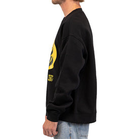 A person in a black unisex Cactus Crew sweatshirt by Icelantic Skis, featuring a yellow graphic on the front and paired with light blue jeans, stands facing left, shown from the waist up against a white background. The Cactus Crew is crafted from recycled polyester fleece for comfort and sustainability.