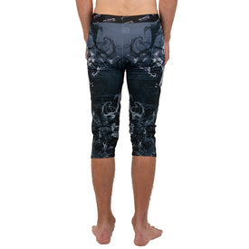 A person standing barefoot, shown from behind, wearing Icelantic Skis Astronaut Wikmax Baselayer 3/4 Bottom leggings in a black and gray pattern made with advanced WIKMAX fabric that reach mid-calf.