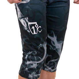 Close-up of a person wearing the Icelantic Skis Astronaut Wikmax Baselayer 3/4 Bottom, featuring black fabric with white smoke-like patterns and a white 1°C logo on the left thigh. Only the lower torso and legs are shown, emphasizing the innovative Wikmax fabric engineered for optimal performance.