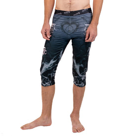 An individual stands barefoot on a white background, wearing Icelantic Skis' Astronaut Wikmax Baselayer 3/4 Bottom—compression pants in a black and gray smoke pattern that extend below the knees and are crafted from advanced WIKMAX fabric.