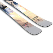 Close-up of two light-colored Icelantic Skis with a pastel sky design, showing the tips. The ski on the right is labeled Nomad 112 and features several small logos and symbols near the tip.