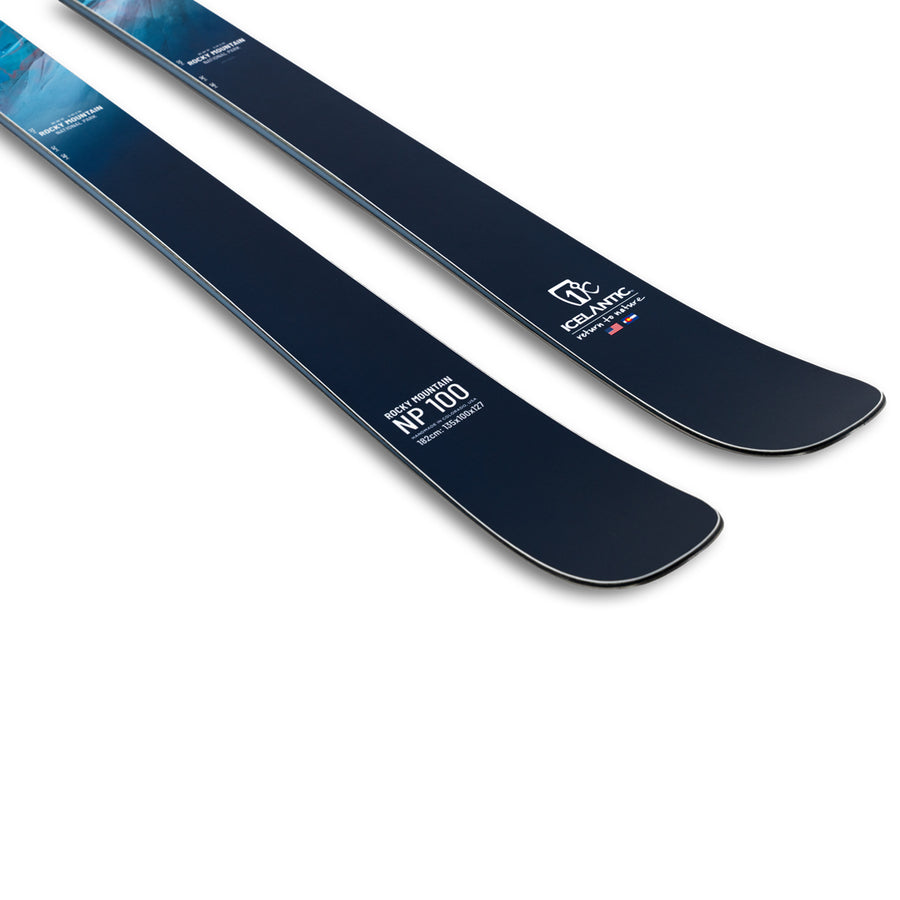 A close-up of two dark blue Rocky Mtn NP 100 skis by Icelantic Skis features bold white text displaying the model name and “Equilibre.” The all-mountain skis are positioned parallel on a white background, highlighting their sleek design and exceptional handmade craftsmanship from Colorado.