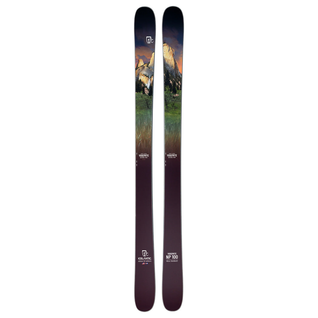 A pair of Icelantic Skis Yosemite NP 100 all-mountain skis, handmade in Colorado, featuring a scenic landscape graphic with mountains, green trees, and a sunset sky. The skis transition from a dark base to lighter tones toward the top, with logos and model information displayed near the bottom.