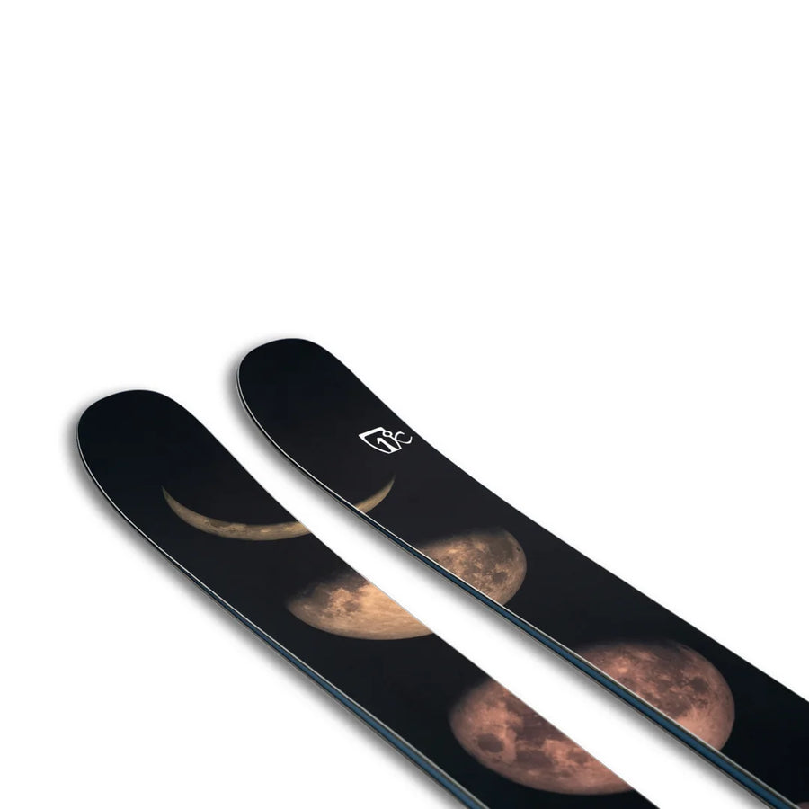 A pair of Icelantic Skis Maiden 102, featuring black bases and moon phase graphics on the tips, set against a white background.