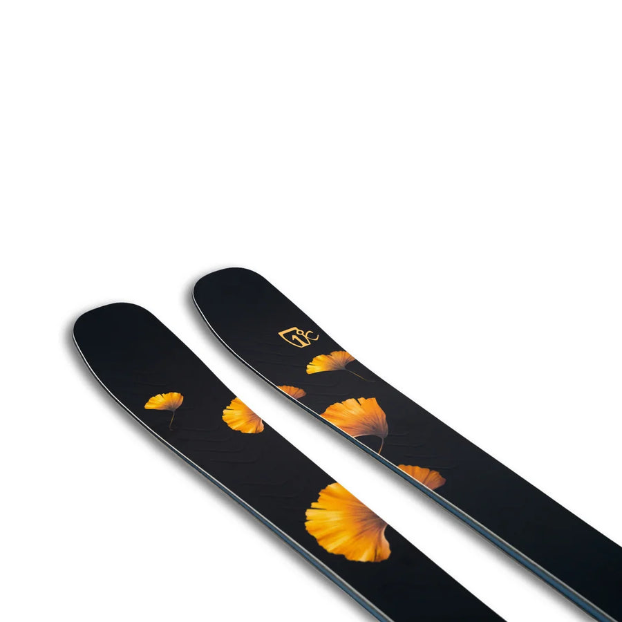 A pair of Tempest 88 skis by Icelantic Skis, featuring a black base adorned with yellow-orange ginkgo leaf patterns near the tips, set against a white background.