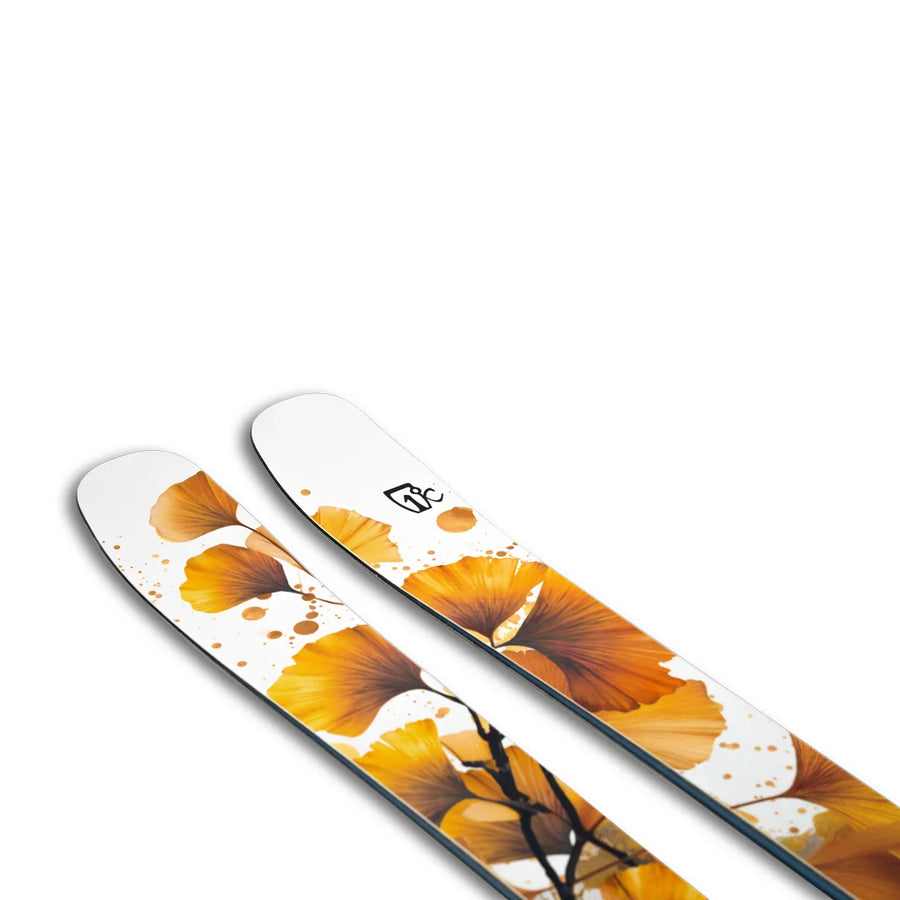 The Icelantic Skis Tempest 94 is a pair of white skis adorned with a vibrant yellow and orange ginkgo leaf design, accented by black stems and abstract orange splashes on the surface.