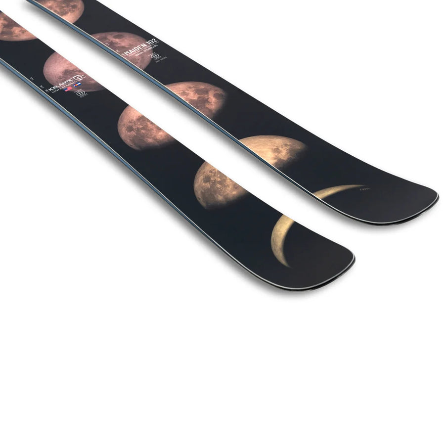 A pair of Icelantic Skis Maiden 102 black skis featuring a design of the moon’s phases, from crescent to full moon, printed along the top surface near the tips.