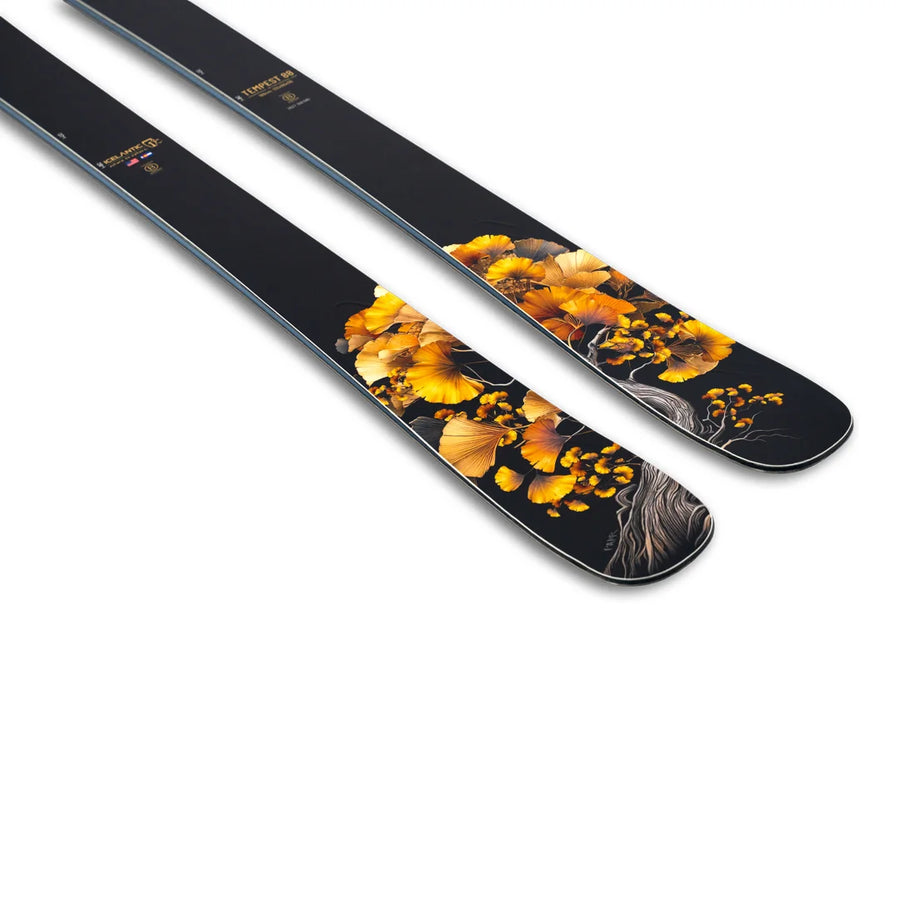 A pair of Icelantic Skis Tempest 88 skis featuring a decorative design of yellow and orange ginkgo leaves and branches near the tips on a white background.