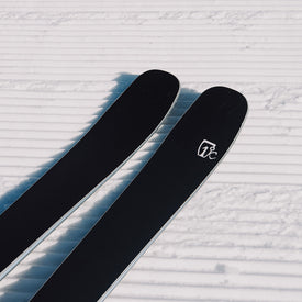 Two black Torrent 88 skis from Icelantic Skis, featuring a white logo, rest on freshly groomed, corduroy-patterned snow—promising an agile ride and all-mountain performance for those seeking adventure on every run.