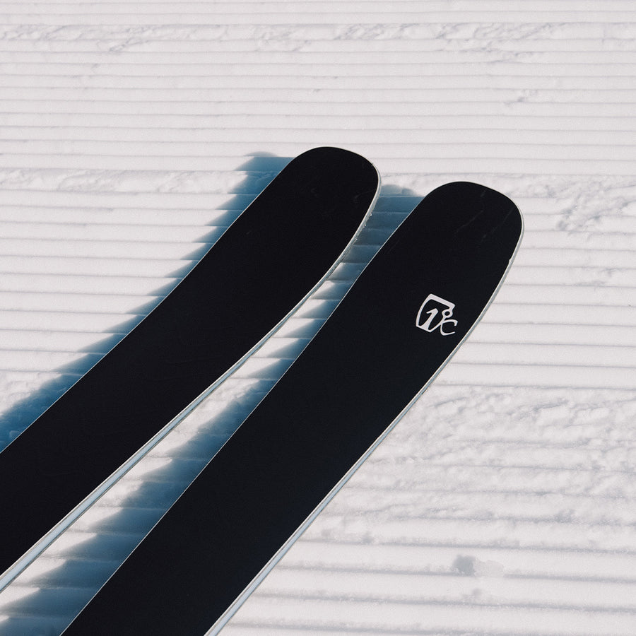 Two black Torrent 88 skis from Icelantic Skis, featuring a white logo, rest on freshly groomed, corduroy-patterned snow—promising an agile ride and all-mountain performance for those seeking adventure on every run.