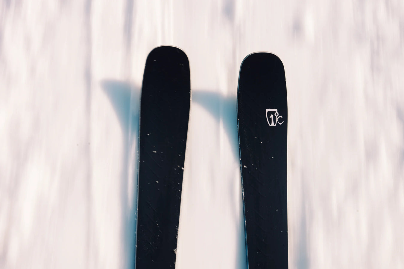 A close-up, top-down view of two black Icelantic Skis Torrent 88 skis on snow, with one ski displaying a white logo near its tip.