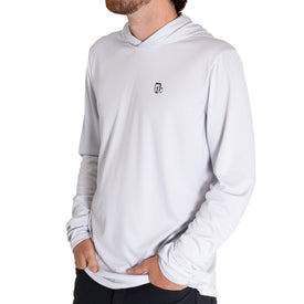 A person wearing the Icelantic UV Sun Hoodie - Cowboy in light gray, with hands in pockets and facing slightly to the side. The hoodie offers UPF 50 sun protection and features a small black Icelantic logo on the left chest. The background is white.