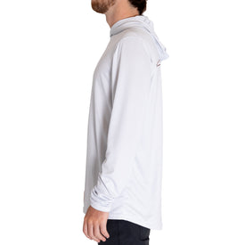 A man is standing in profile against a plain white background, wearing the Icelantic UV Sun Hoodie - Cowboy in light gray along with dark pants.