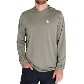 A man is wearing the Icelantic UV Sun Hoodie in Olive Grey, featuring a small white logo on the chest and paired with black pants. Made from UPF 50 fabric for superior sun protection and quick dry technology for all-day comfort, his right hand is in his pocket while his face is partially out of frame.