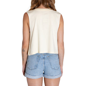 A woman is shown from the back, wearing the Icelantic Cactus Cropped Tank in linen paired with high-waisted, light blue denim shorts—perfect for summer. She has long hair and a small tattoo on her left arm, set against a plain white background.