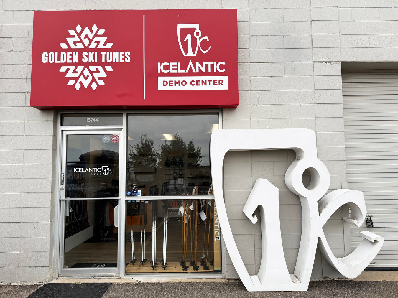 A storefront with signs reading Golden Ski Tunes and Icelantic Demo Center. Skis are visible through the glass door, and large white Icelantic logo sculptures lean against the building.