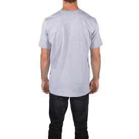 Wearing the ultra-soft Icelantic Logo Tee - Grey from Icelantic Skis, styled with black jeans, a person stands with their back to the camera against a white background. This unisex t-shirt combines comfort and versatility, making it a perfect addition to any wardrobe.