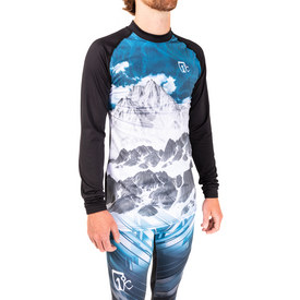 A man wearing the Icelantic 23/24 Men's WikMax Baselayer Top with a mountain and clouds design from the Pioneer Collection stands against a white background.