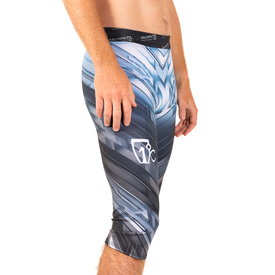 A person is shown from the waist down and side view, wearing Icelantic's 23/24 Men's WikMax Baselayer 3/4 Bottoms featuring an abstract blue, gray, and white pattern; crafted from advanced WIKMAX fabric and with their left arm resting by their thigh, these versatile leggings deliver ski-pant-level performance for active pursuits.