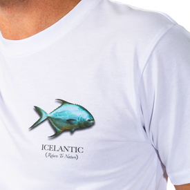 A person wearing the Icelantic Permit Tee—a white unisex t-shirt featuring a blue fish graphic and "ICELANTIC (Return To Nature)" text on the chest. Made from organic cotton, this tee is an eco-friendly choice for a casual look.