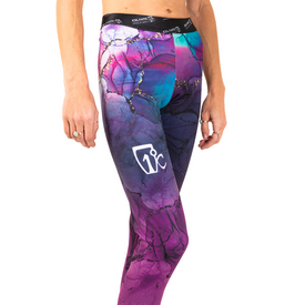 A person is wearing Icelantic 23/24 Womens WikMax Baselayer Full Bottom leggings featuring a colorful, abstract pattern and a white logo on the thigh, standing against a white background with only their lower torso and legs visible.