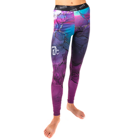 A person models the Icelantic 23/24 Women's WikMax Baselayer Full Bottom leggings in a vibrant purple and blue marble pattern, featuring a white logo on the left thigh, standing barefoot against a white background.
