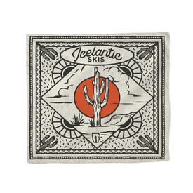 The Cactus Bandana by Icelantic Skis features a central cactus with a red sun and cloud design. Made from lightweight cotton, it showcases a decorative border with small cacti in each corner and bold "Icelantic Skis" script at the top. This bandana comes in cream, black, and orange colors and is proudly made in Denver.