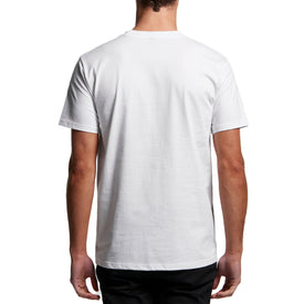 A person is shown from the back, standing against a white background, wearing the Icelantic Skis Cowboy Killer Pocket Tee—a plain white heavyweight cotton shirt with short sleeves—and black pants.