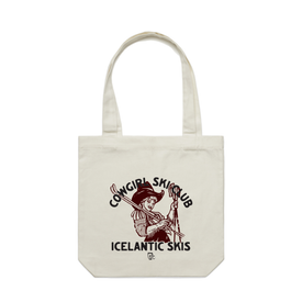 Introducing the Cowgirl Ski Club Tote by Icelantic—a white cotton canvas tote bag featuring an illustration of a cowgirl holding skis. The text "Cowgirl Ski Club Icelandic Skis" appears above and below the image. Sturdy and spacious, this tote is perfect for carrying your essentials in style—an ideal accessory for every Cowgirl Ski Club Tote fan.