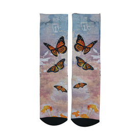 A pair of Icelantic 22/23 Maiden Socks featuring an artistic design with orange monarch butterflies and yellow flowers set against a soft, cloudy blue and pink background, inspired by Travis Parr’s vibrant Maidens artwork.