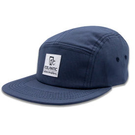 The RTN 5-Panel - Navy by Icelantic Skis is a navy blue five-panel hat made from durable cotton twill, featuring a flat brim and a rectangular white patch on the front that displays the Icelantic logo along with their slogan, "Return to Nature.