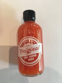 A clear bottle of Icelantic Skis Original Hot Pepper Sauce with a black cap and vibrant orange-red sauce inside, displayed against a plain white background.
