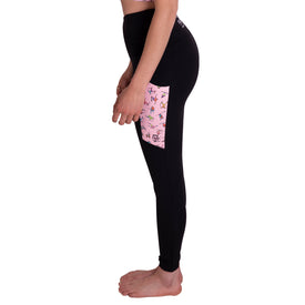 A person stands sideways against a white background, barefoot, wearing Icelantic's Skier Pocket Legging in Black/Pink—high-waisted, eco-friendly leggings made from recycled polyester and featuring a pink pocket adorned with small animal illustrations.