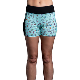 A person wearing the Icelantic Skier Pocket Short - Mint, women’s pocket shorts in light blue with colorful bird patterns and a black waistband, crafted from recycled fabric, shown from the waist to mid-thigh against a white background.