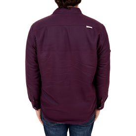 A person facing away, wearing the Icelantic Sherpa Lined Jacket in deep purple paired with blue jeans, stands against a white background.