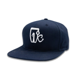 The Icelantic One Degree Snapback Hat - Navy is made from classic cotton twill and features a flat brim with a white embroidered "Vic" logo on the front panel.