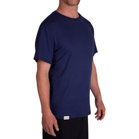 A man, dressed in the Icelantic SoftTECH T - Navy featuring advanced wicking technology for enhanced comfort and paired with black pants, stands slightly turned to the side against a white background.