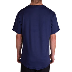 A person with long hair is shown from behind wearing the Icelantic SoftTECH T - Navy, a plain navy blue short-sleeve t-shirt paired with black pants, standing against a white background. The SoftTECH T combines advanced wicking and antimicrobial properties to keep you feeling fresh and comfortable all day.