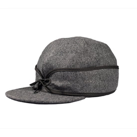 A gray wool Stormy Kromer Cap by Icelantic, this classic winter hat features a short, rounded brim with black trim and is accented by a black string tied in a bow above the brim. Its soft, structured shape offers both style and functionality for colder weather.
