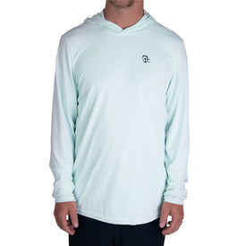 A person wearing the Icelantic UV Sun Hoodie in Clearly Aqua, featuring a small black logo on the left chest, stands against a plain white background. This UPF 50 long-sleeve hoodie provides excellent quick-dry performance for all-day comfort.