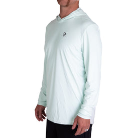 A man stands at an angle with his hands relaxed by his sides against a plain white background, wearing the Icelantic UV Sun Hoodie in Clearly Aqua—a lightweight, long-sleeve sun protective hoodie featuring a small chest logo and UPF 50 for added protection.