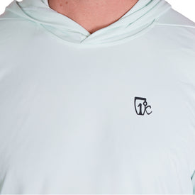 A person wearing the Icelantic UV Sun Hoodie in the Clearly Aqua color, featuring a small black stylized "Tic" logo on the left chest. The quick-dry hood is down, revealing only the neck and upper chest.