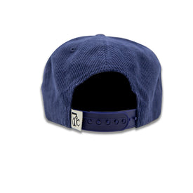 A navy blue Rocky Mountain Corduroy Hat by Icelantic Skis is shown from the back, featuring a classic snapback closure for a customizable fit and a small white tag with the Icelantic logo on the left side. Inspired by the rugged beauty of Rocky Mountain National Park, this cap blends timeless style with adventure-ready comfort.