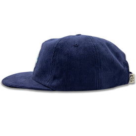 The Rocky Mountain Corduroy Hat by Icelantic Skis is displayed in profile on a white background, featuring a navy blue corduroy design with a flat brim and an adjustable snapback closure at the back—a perfect choice for fans of classic corduroy hats.