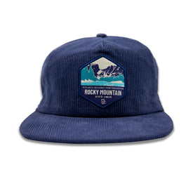 Introducing the Rocky Mountain Corduroy Hat by Icelantic Skis—a blue corduroy cap featuring a patch with mountains and the text "Icelandic National Park Collection Rocky Mountain Est. 1918." Designed with a classic snapback closure, this stylish hat is the perfect tribute to Rocky Mountain National Park.